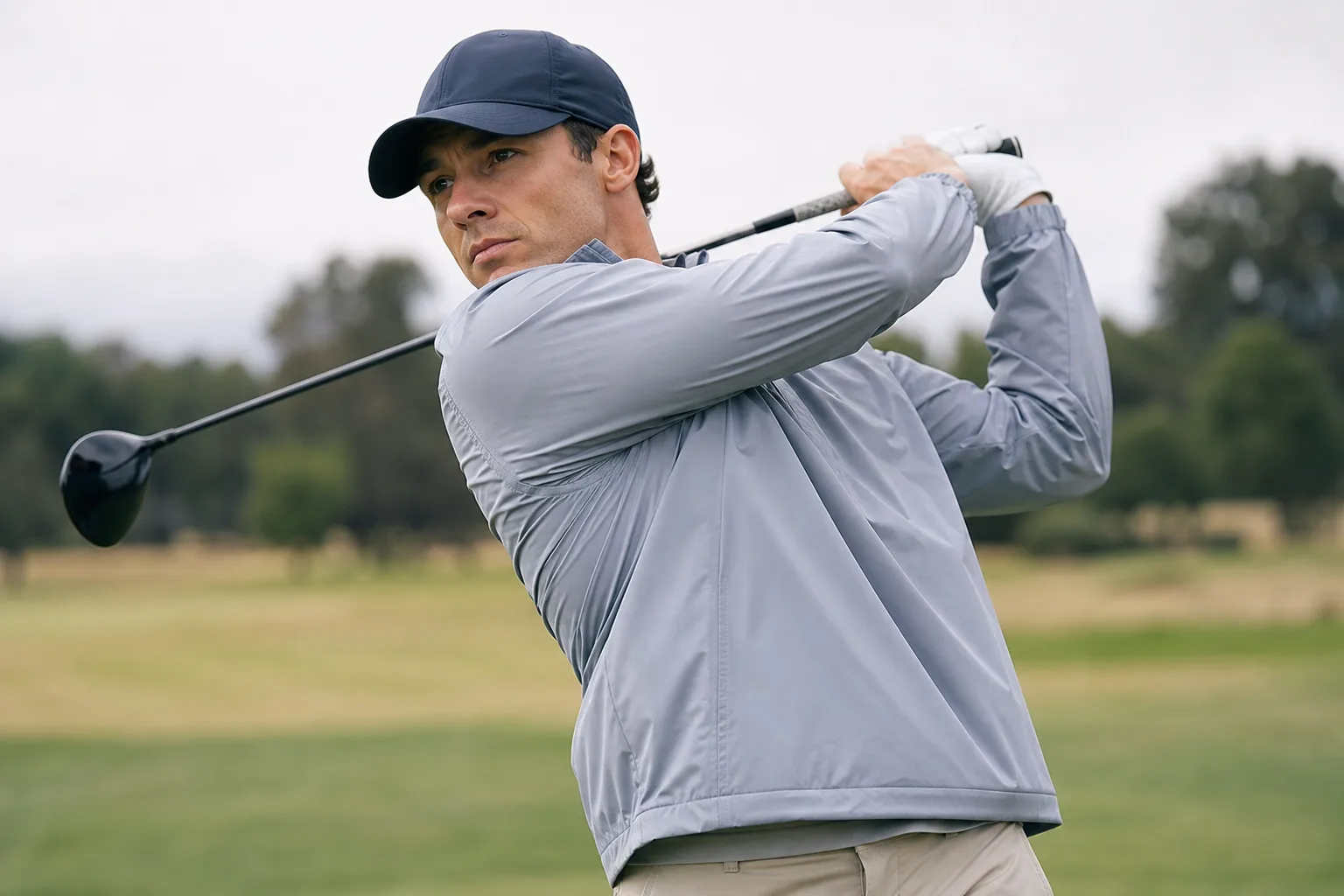 Golfer mid-swing wearing a lightweight windbreaker to show mobility